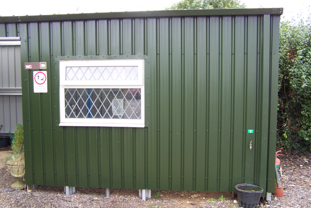 The side of a green building with a white window