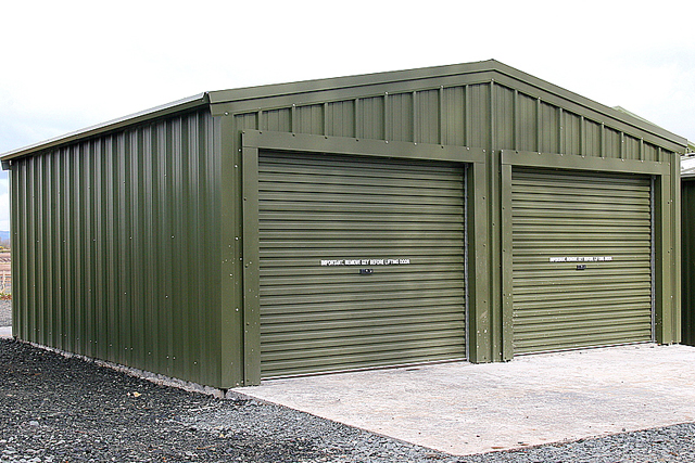 A green building with two closed roller doors